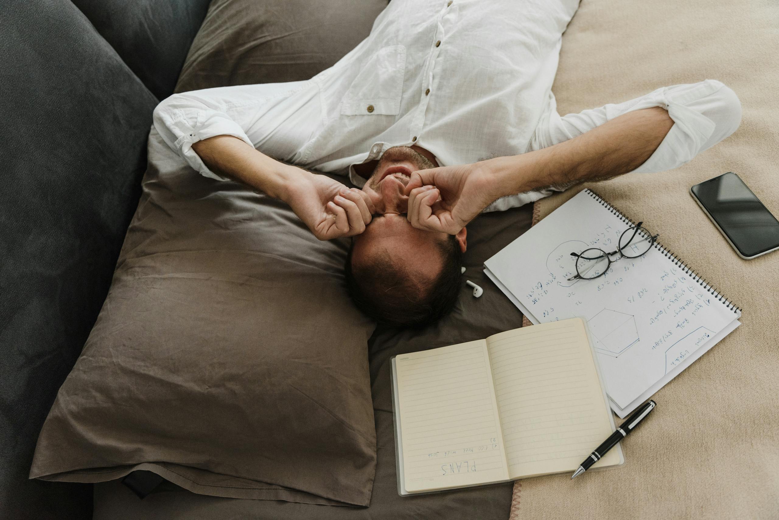 An Exhausted Man Lying on Bed Rubbing his Eyes