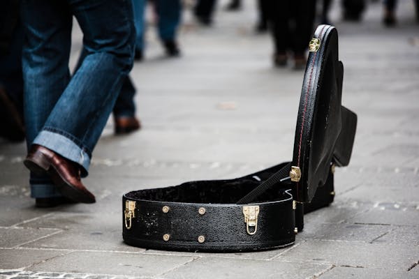 Black Guitar Case on Concrete Pathway With People Walking during Daytime