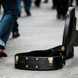 Black Guitar Case on Concrete Pathway With People Walking during Daytime