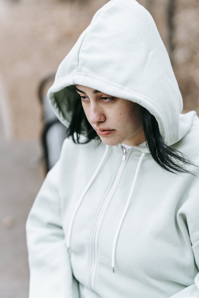 Upset young woman in hood sitting on bench